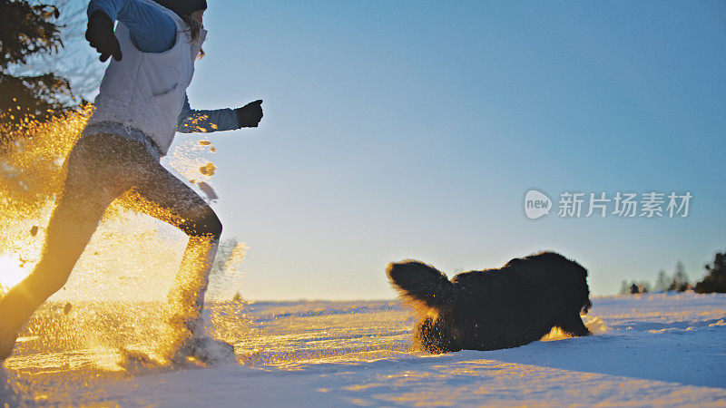 一位女士和她的宠物狗在雪地上走雪鞋