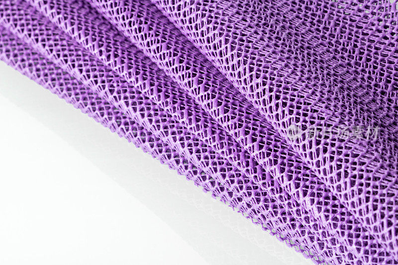 一张淡紫色的合成厨房餐巾在白色的背景上折叠起来，像一把扇子