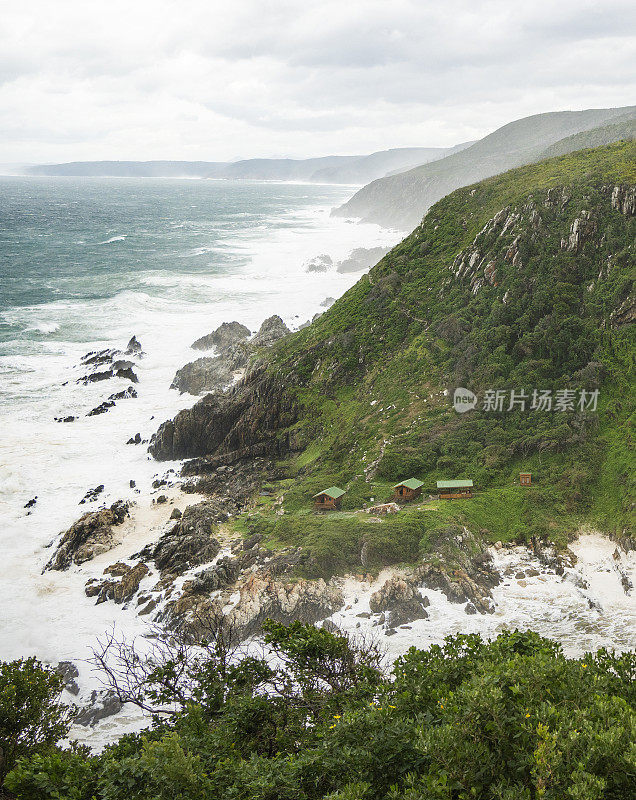 小屋坐落在多岩石的海岸线上，海浪汹涌