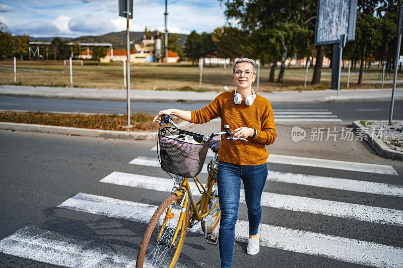 一个留着短发的白人女人在她的自行车旁走过城市