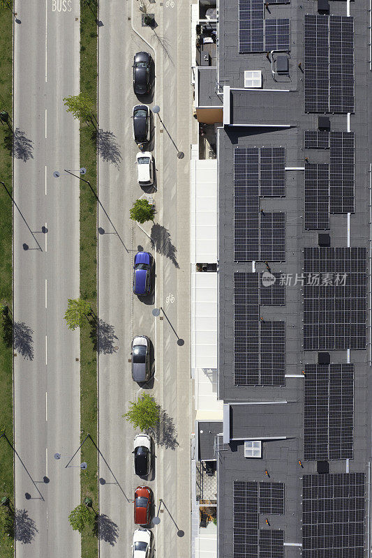 街边停车场，旁边是一栋装有太阳能电池板的公寓楼