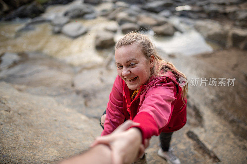 年轻的女徒步旅行者伸出手寻求队友的帮助