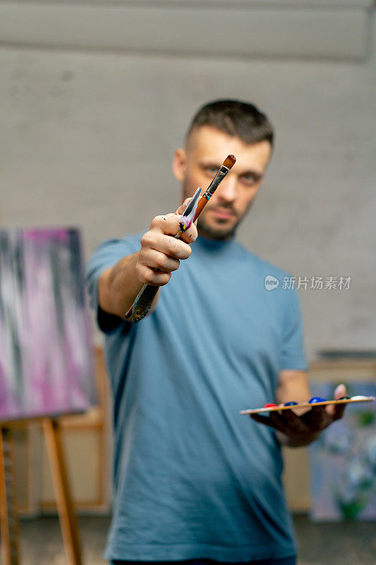 在艺术工作室里，艺术家用眼睛直接对着相机用画笔测量