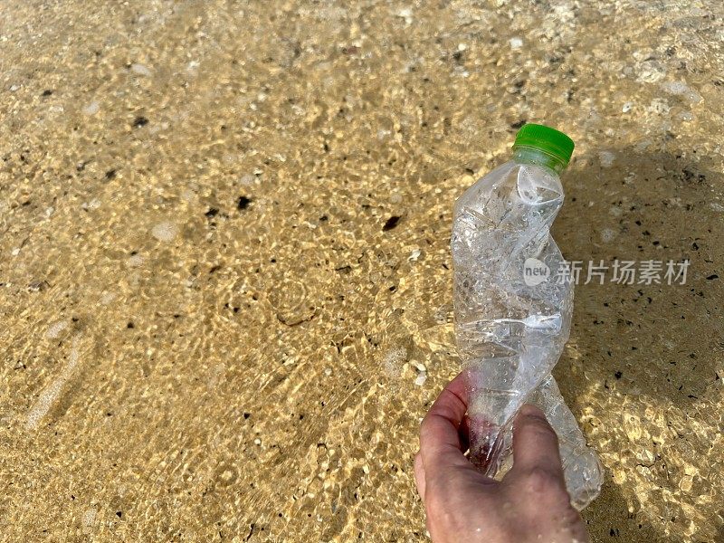 手从海滩上捡了一个塑料瓶
