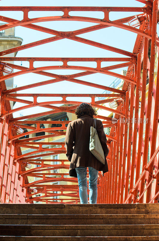 女人走过一座铁桥。