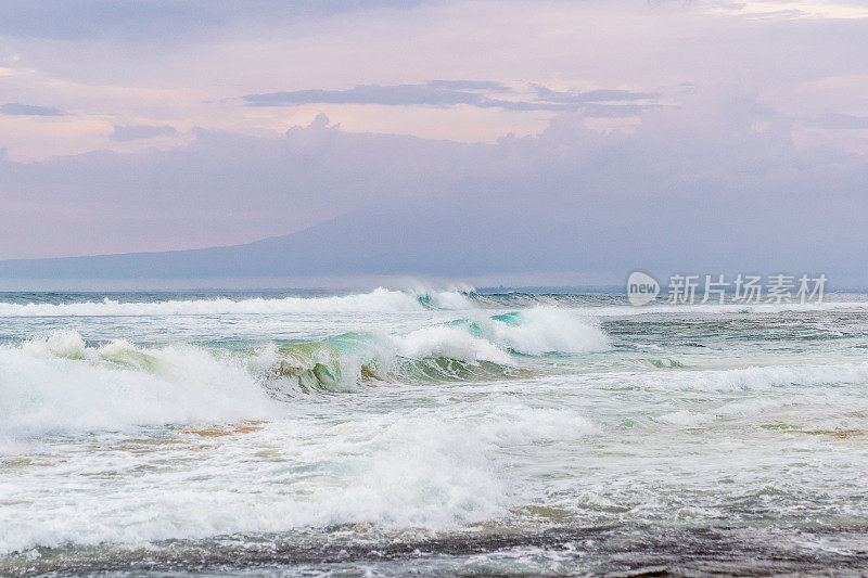 蓝绿色的海浪在多云的天空下撞击。巴厘岛，梦幻海滩。