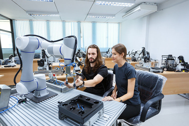 自动化机械工程专业的学生在大学机器人工程学院或工厂车间学习和检测控制机器人手臂机械。AI机器人技术，未来创新趋势。