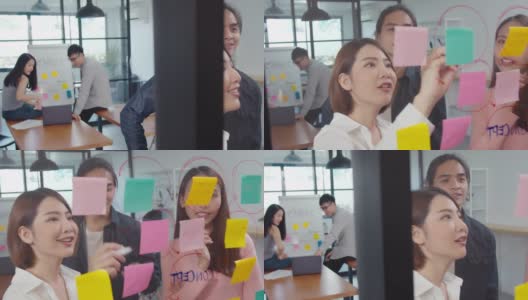 年轻的亚洲女性和她的同事在现代办公室的玻璃墙上用便利贴写想法高清在线视频素材下载