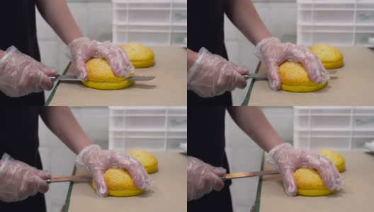 一名戴着手套的男子用刀将一个芝麻小面包切成两半高清在线视频素材下载