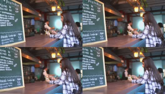 一名年轻女子在酒吧柜台使用智能手机高清在线视频素材下载