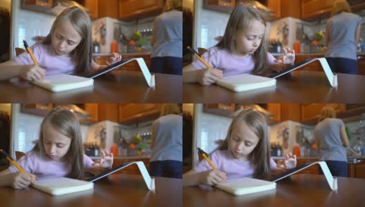 金发女孩在笔记本上写字，在平板电脑上浏览。高清在线视频素材下载