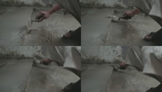 男人的手正在用泥铲抹地板。建筑工人在家。高清在线视频素材下载