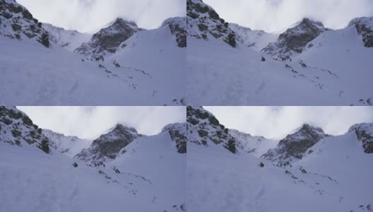 在寒冷的阳光明媚的天气里，滑雪游览覆盖在雪中的岩石山脉景观高清在线视频素材下载