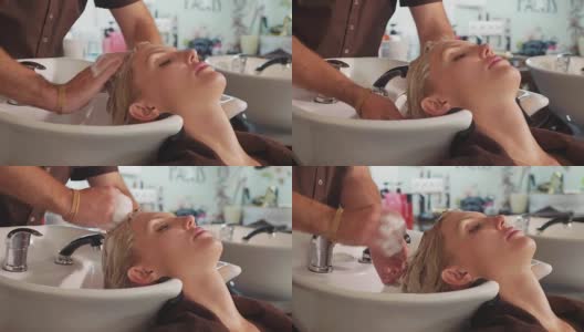 男发型师在现代美容院给一个金发女人洗头高清在线视频素材下载