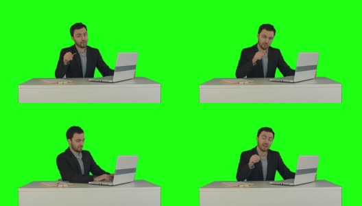 快乐的商人坐在办公室里拿着笔记本电脑对着绿色屏幕的摄像头说高清在线视频素材下载