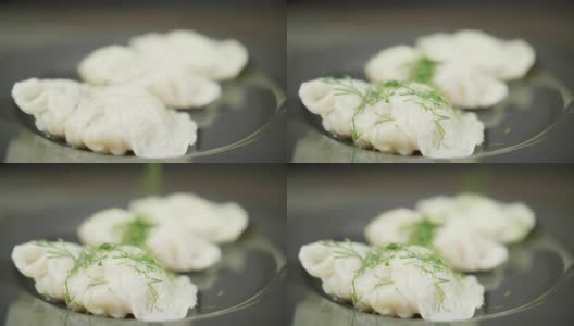 厨师在煮熟的饺子上洒上绿叶高清在线视频素材下载