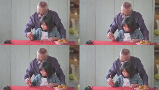 亚洲华人小女孩向她的祖父学习写中国书法高清在线视频素材下载