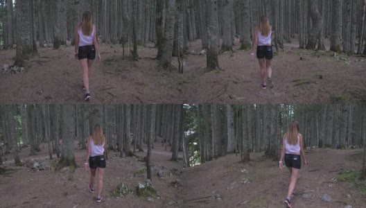 在运动中，一个年轻的女人走在黑松林背面观看4K高清在线视频素材下载