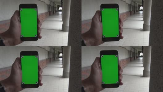 4K白人男子显示绿色屏幕手机在过道与柱高清在线视频素材下载