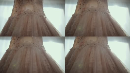 豪华现代婚纱挂在窗口。时尚的粉彩婚礼礼服蕾丝花的细节高清在线视频素材下载