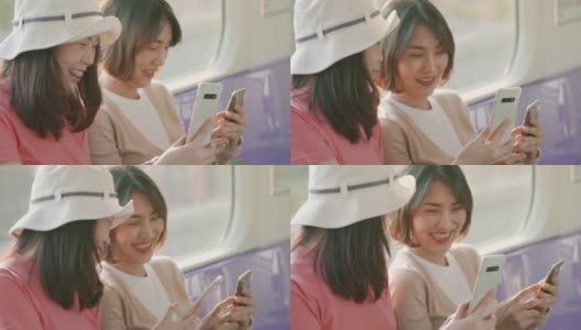 两个年轻的亚洲女人在火车上一边聊天一边用手机，慢镜头高清在线视频素材下载