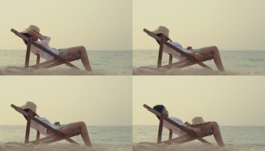 年轻的亚洲女性感觉放松躺在沙滩上的躺椅上有软呢帽接近她的脸。夏天度假的概念。高清在线视频素材下载