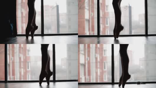 美丽的芭蕾舞脚尖角鞋，剪影对着窗户和城市。芭蕾舞女演员优美的步态。缓慢的运动。特写镜头。高清在线视频素材下载