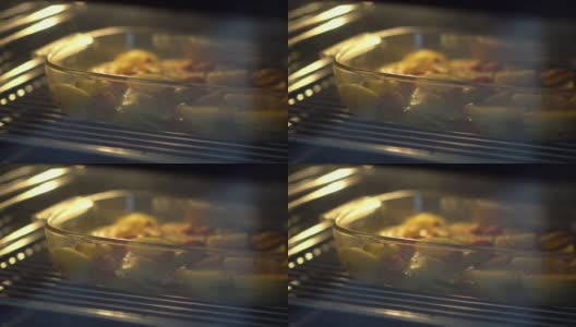 一盘肉和土豆放在烤箱里的玻璃碗里烤着高清在线视频素材下载