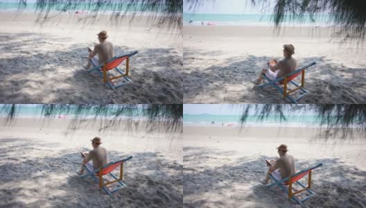 在夏日阳光灿烂的日子里，4K亚洲男人躺在沙滩椅上休息。高清在线视频素材下载
