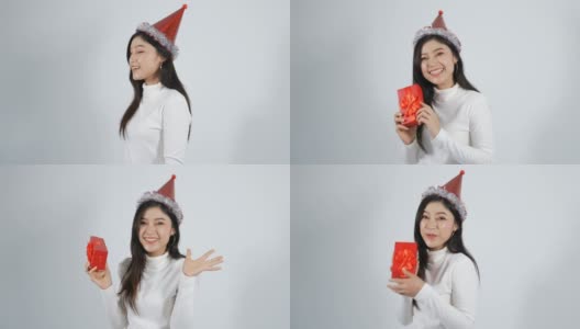 快乐的年轻女人戴着帽子，拿着白色背景上的红色圣诞礼盒高清在线视频素材下载