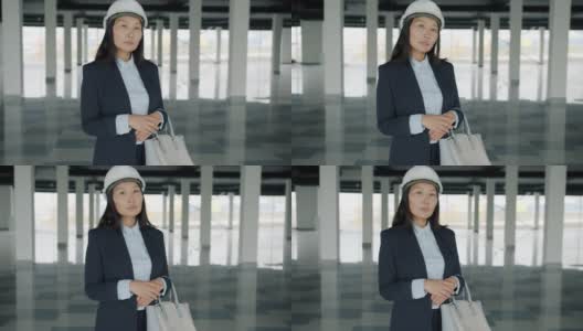 亚洲年轻女士的慢动作肖像建筑投资者站在新大楼戴着头盔高清在线视频素材下载