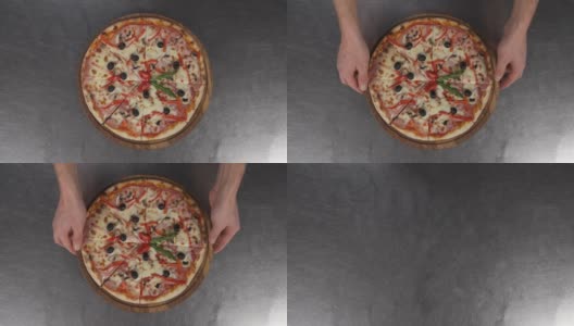 男性的手拿着一块美味的比萨饼木板的特写。典型的意大利披萨。意大利菜的概念，餐厅披萨的传统高清在线视频素材下载