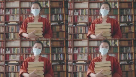 积极的亚洲学生戴着口罩，拿着一叠书，在流行病期间教育高清在线视频素材下载