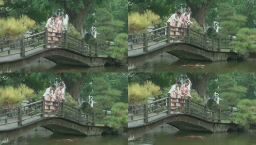 女孩们穿着汉服，在公园喂锦鲤。高清在线视频素材下载