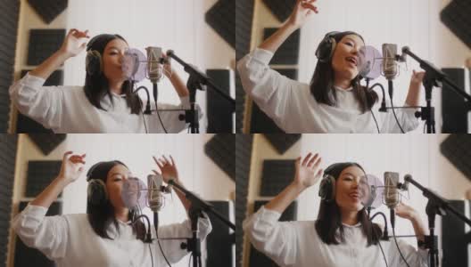 新的轨道。精力充沛的亚洲女歌手在音乐工作室录制歌曲高清在线视频素材下载