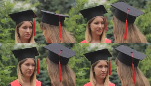 两名女毕业生在毕业典礼后穿着学术服装交谈高清在线视频素材下载