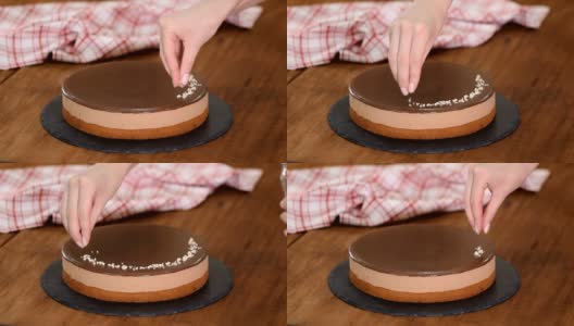 女人在巧克力慕斯蛋糕上点缀坚果。高清在线视频素材下载