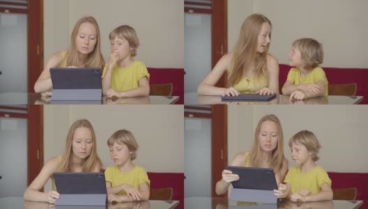 一位年轻妇女和她的小儿子在隔离期间坐在家里，在互联网学校使用平板电脑学习。冠状病毒的概念高清在线视频素材下载