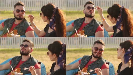 一对时髦的夫妇坐在城市公园里吃着冰淇淋和华夫饼开怀大笑。浪漫的年轻男女在户外休闲放松。女友给男友高清在线视频素材下载