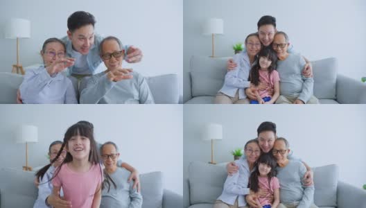亚洲多代人的肖像，家庭花时间在一起在家里。漂亮的老夫妇坐在客厅的沙发上，年轻的男子儿子和孙女微笑着看着家里的相机。高清在线视频素材下载