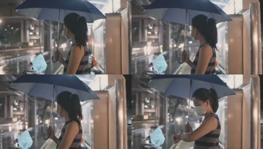 一名亚洲女子撑着伞在公交车站等车高清在线视频素材下载