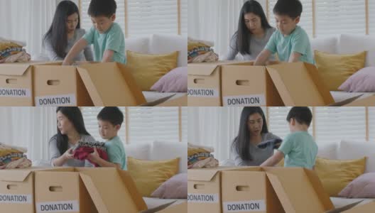 亚洲妈妈和孩子准备在家里捐赠旧衣服包装盒。高清在线视频素材下载