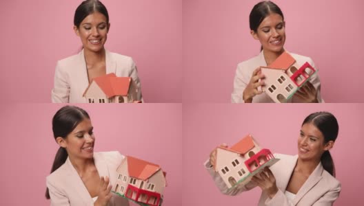 快乐的年轻女商人在粉红色的西装拿和推荐房子模型，点头和赞成在粉红色的背景高清在线视频素材下载