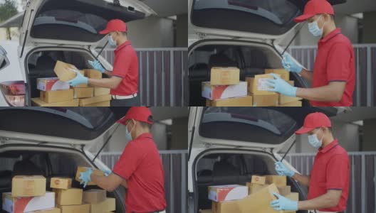 4 k慢动作视频。一名穿着红色制服的男性快递员寄包裹盒子在村里的汽车后备箱里喷洒清洁酒精新标准的概念。高清在线视频素材下载