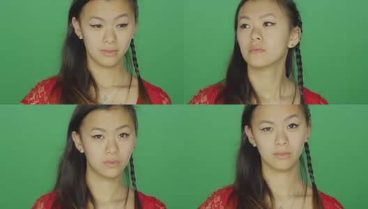 一个年轻的亚洲女人盯着，看起来很严肃，在一个绿色屏幕的工作室背景高清在线视频素材下载