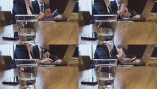 一张桌子上放着一杯水和一部iPhone的特写高清在线视频素材下载