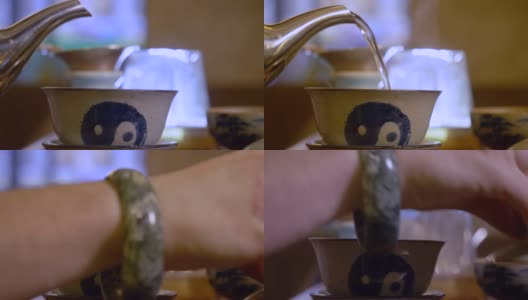 在中国茶道上，男子的手从茶壶里倒热水到盖碗里，这是由宜兴陶土手工绘制的阴阳标志高清在线视频素材下载