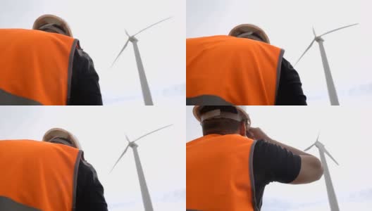 一名男性工程师正在对风力涡轮机进行检查和检查，风力涡轮机通过风力旋转叶片来发电，风力发电机，电力工业高清在线视频素材下载