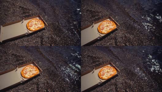 在卵石滩上放着披萨的纸箱。高清在线视频素材下载