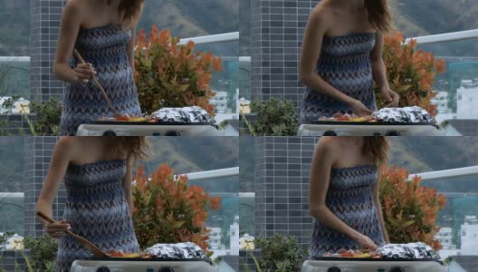 女孩烹饪食物在屋顶露台的火盆下的风高清在线视频素材下载